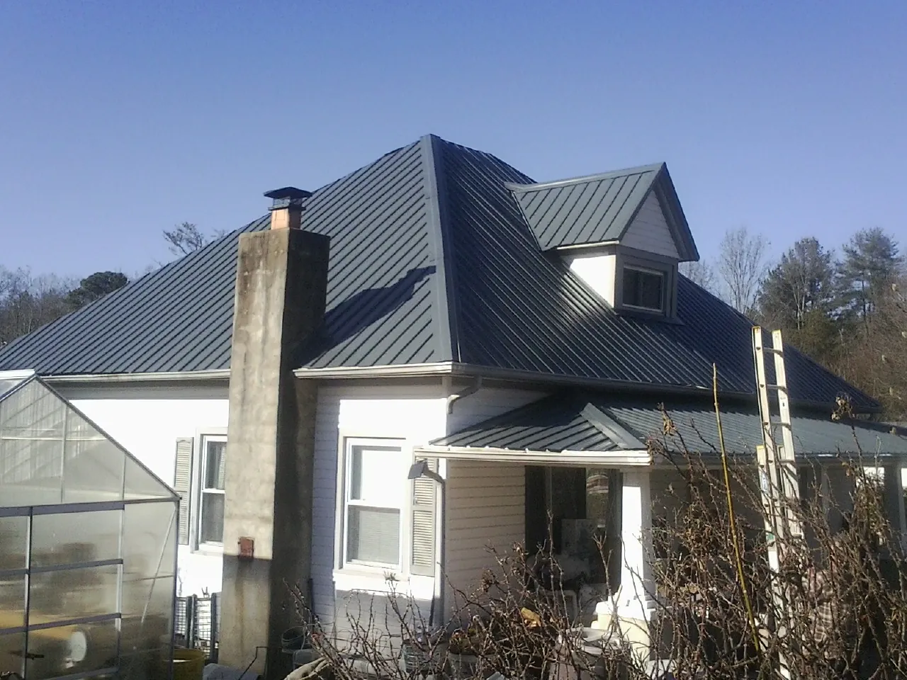 Dark blue standing seam metal roof on a white farmhouse with dormer — Slate & Tile Roof Repair by Roofing Brothers in Fairlee