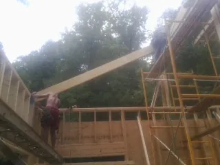 Carpenter raising a rafter beam on a new second story frame in Fairlee