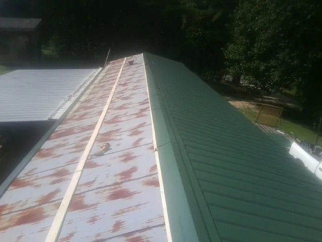 Old rusted panels beside newly installed green metal roofing — Wind Damage Roof Repair by Roofing Brothers in Fairlee