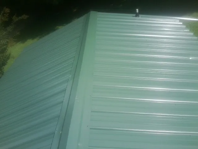 New green metal panels meeting at the ridge of a roof — Flat Roof Repair work by our crew in Fairlee