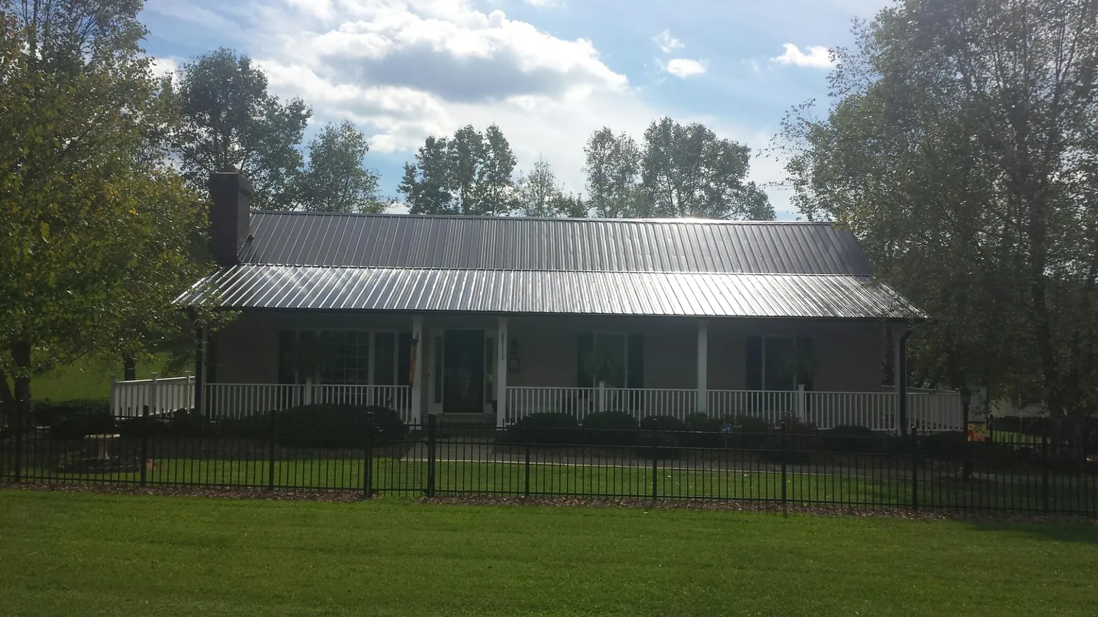 Gray metal roof on a brick ranch with a full width front porch — Gutter Guard Installation work by our crew in Fairlee