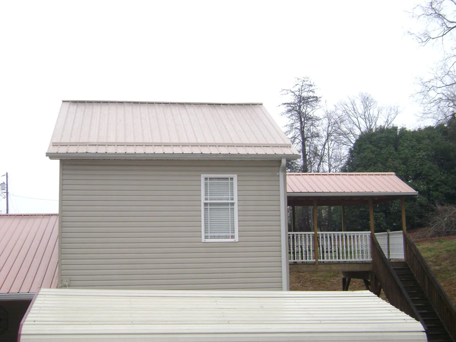 Tan metal roofs on a two story addition and attached porch, from a Roof Replacement job in Fairlee